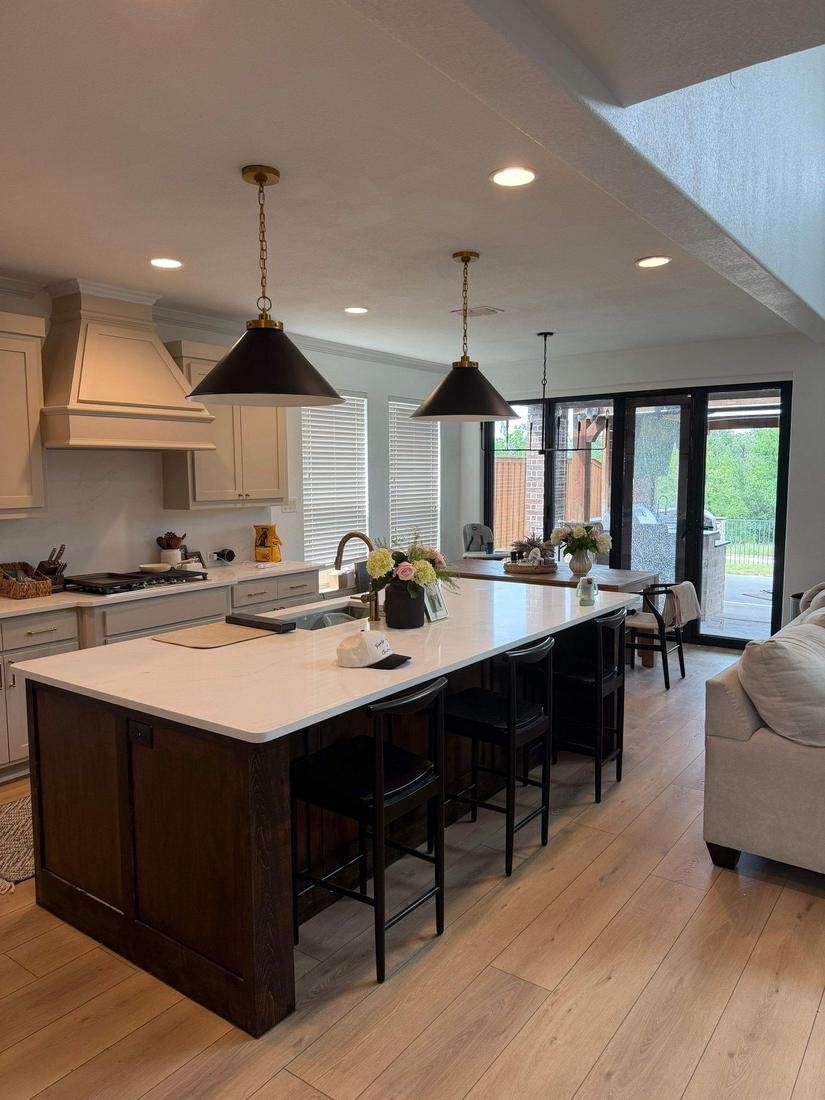 Finished open-concept kitchen with large island, brass pendants and custom bifold patio door