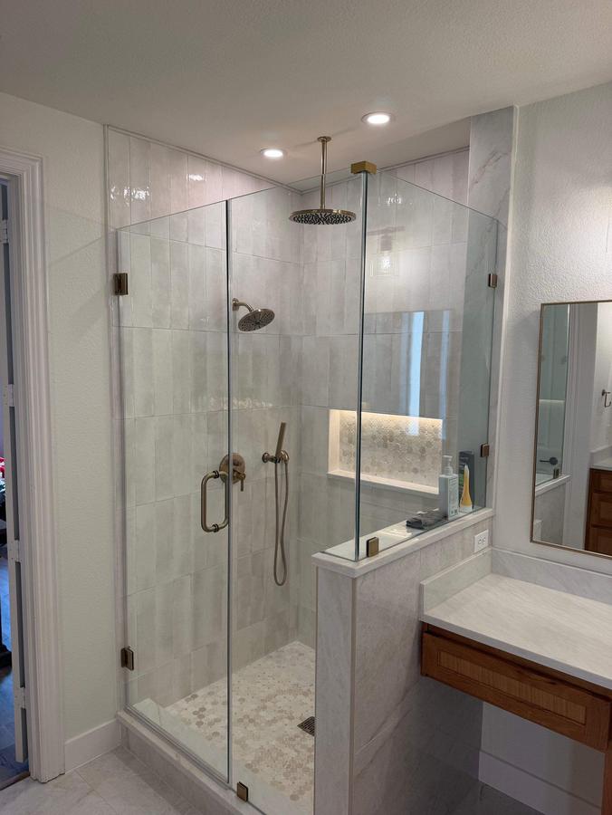 Frameless glass walk-in shower with niche and pebble floor