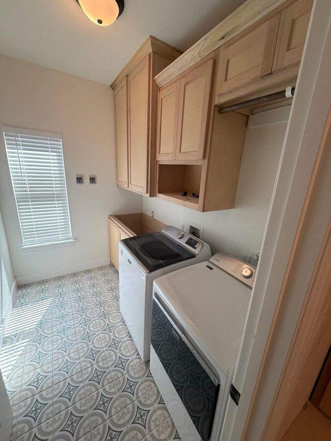 Laundry room with patterned tile floor and wood cabinets