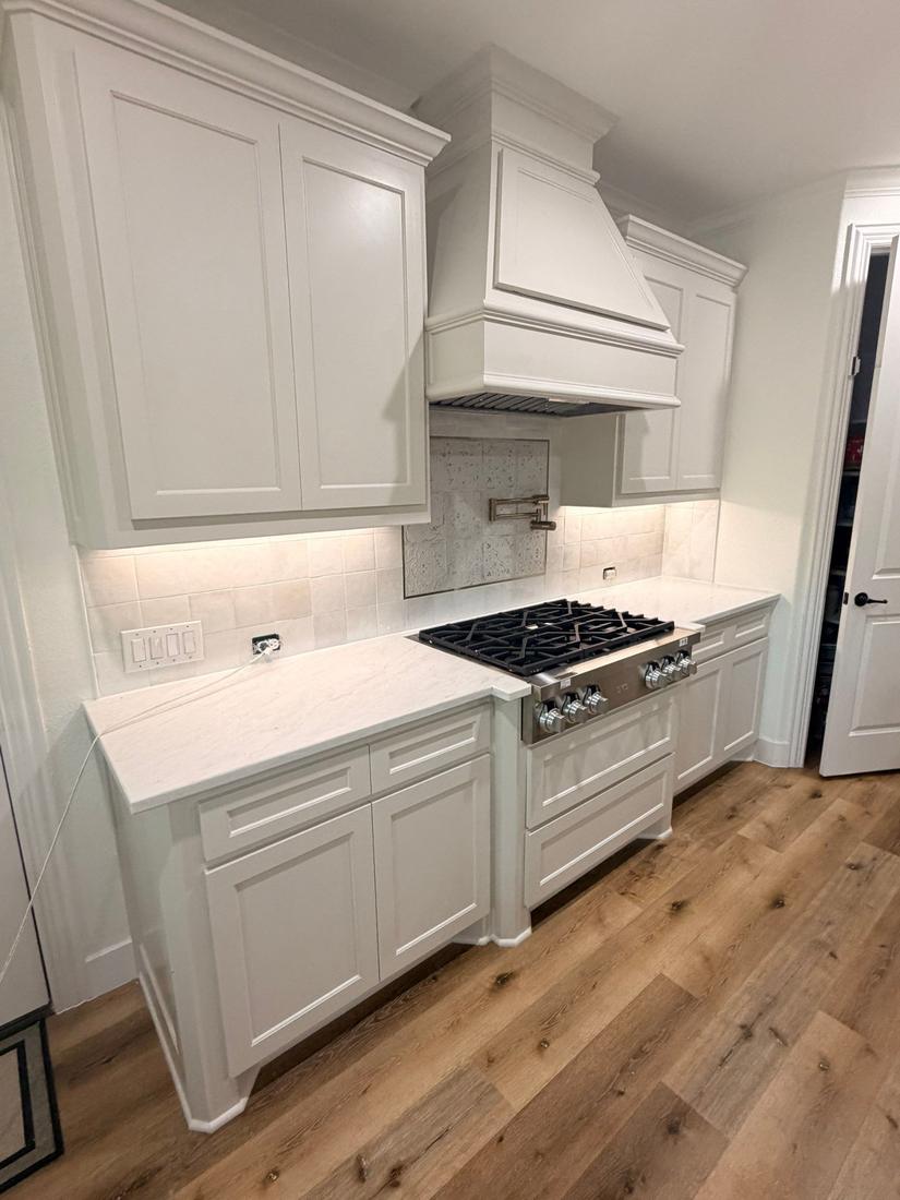 White painted kitchen with range hood, quartzite counters and zellige backsplash
