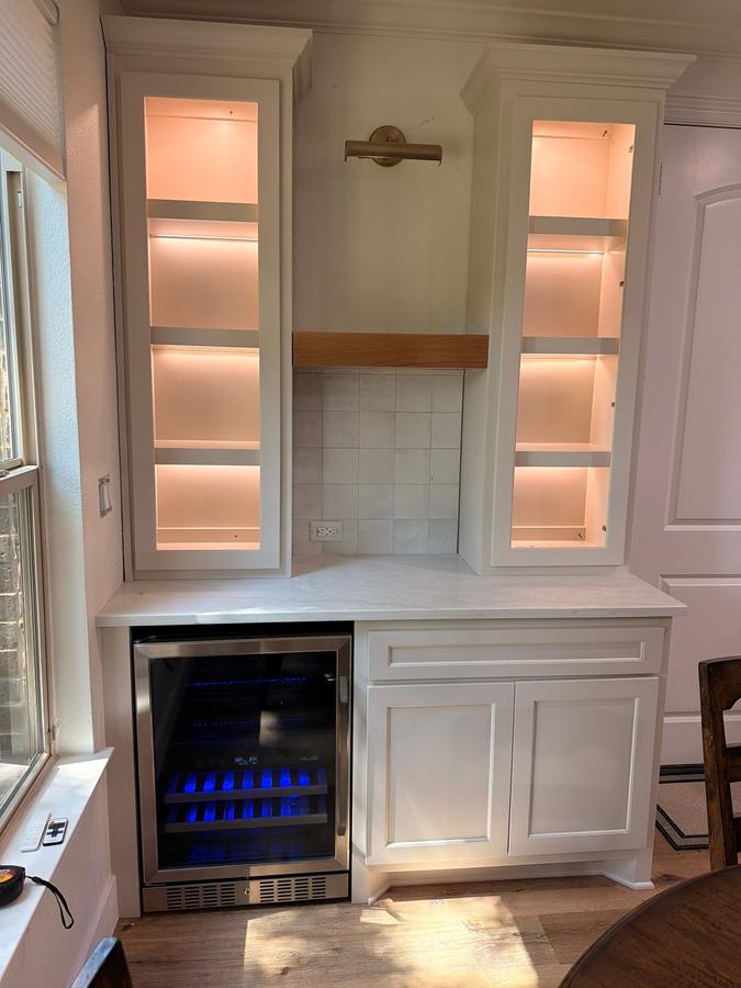 Dry bar with lit glass cabinets and wine fridge