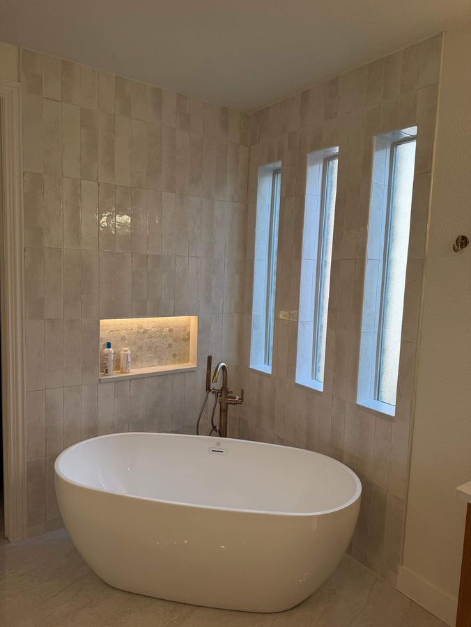 Primary bath with freestanding tub, vertical tile and lit niche