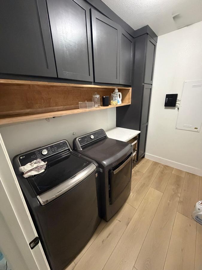 Laundry room with navy cabinets and floating wood shelf